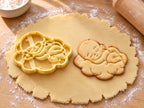 Butter-gelber Ausstecher mit Prägung als Baby auf Wolke neben gebackenem Keks mit schlafendem Baby und bauschiger Wolke auf hellem Holz