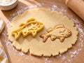 Butter-gelber Barsch-Ausstecher mit Prägung neben gebackenem Keks mit Rückenflosse, Kiemen und Bauchflossen auf hellem Holz