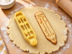 Butter-gelber Bleistift-Ausstecher mit Prägung neben schmalem gebackenem Keks mit Radiergummi und gespitzter Mine auf hellem Holz