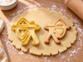 Butter-gelber Bogenschützen-Ausstecher mit Prägung neben gebackenem Keks mit gespanntem Bogen und Pfeil auf hellem Holz