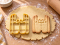 Butter-gelber Anzug-Ausstecher mit Prägung neben Keks mit Revers, Fliege und Knopfleiste auf hellem Holz