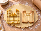 Butter-gelber Anzug-Ausstecher mit Prägung neben Keks mit Revers, Fliege und Knopfleiste auf hellem Holz