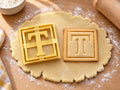 Butter-gelber Ausstecher Buchstabe T mit Prägung neben quadratischem Keks mit Serifen-T im doppelten Rahmen auf hellem Holz