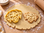 Butter-gelber Dalmatiner-Ausstecher mit Prägung neben gebackenem Keks mit Hundekopf und eingeprägten Tupfen auf hellem Holz