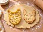 Butter-gelber Schäferhund-Ausstecher mit Prägung neben gebackenem Keks mit Stehohren und Fellkragen auf hellem Holz