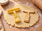 Butter-gelber Farbtuben-Ausstecher mit Prägung neben gebackenem Keks mit stehender Tube und geriffeltem Hals auf hellem Holz
