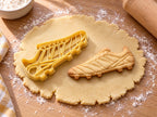 Butter-gelber Fußballschuh-Ausstecher mit Prägung neben gebackenem Keks mit Winkelmuster, Schnürung und Stollen auf hellem Holz