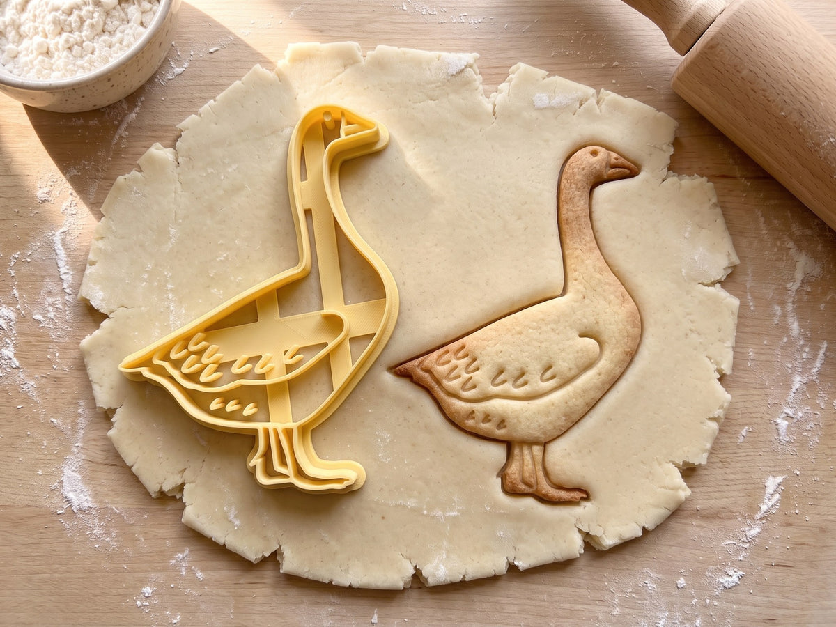 Butter-gelber Gans-Ausstecher mit Prägung neben gebackenem Keks mit langem Hals, Federn und Schwimmfüßen auf hellem Holz