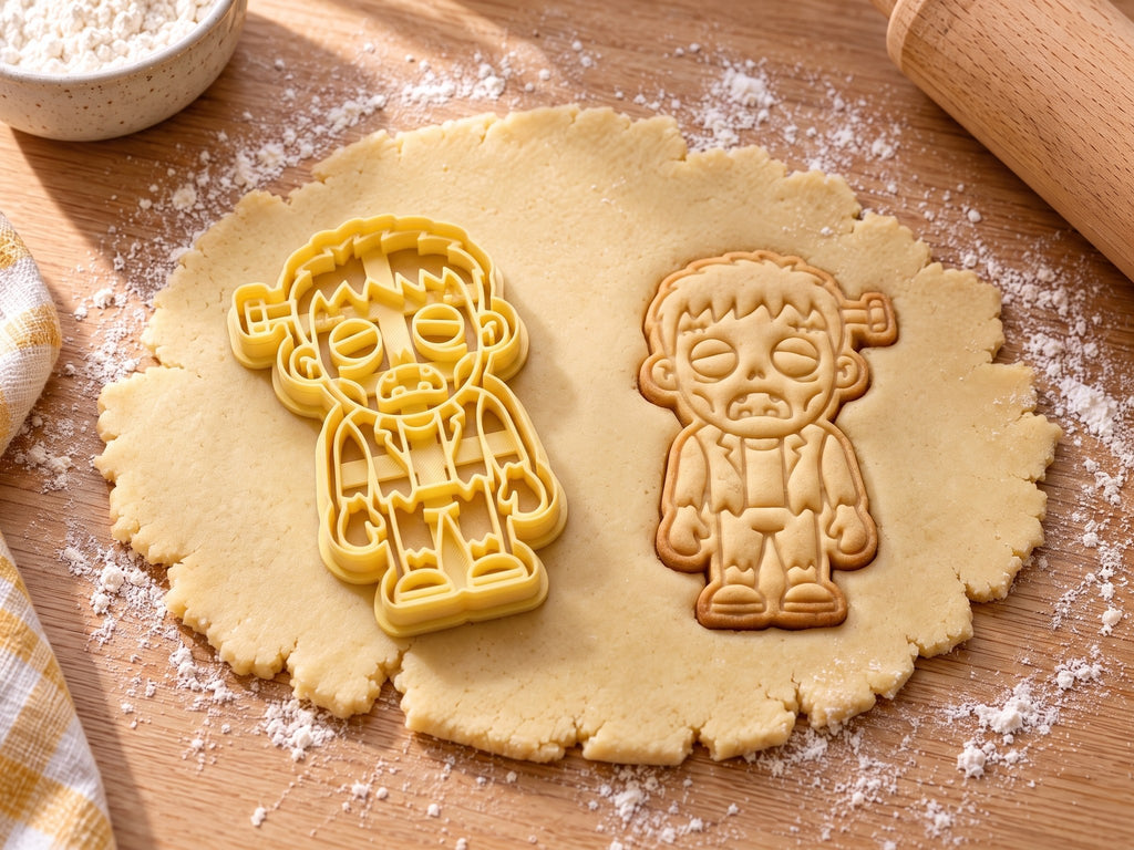Butter-gelber Monster-Ausstecher mit Prägung neben Keks mit Kopfbolzen, Stirnnaht und zerrissener Kleidung auf hellem Holz