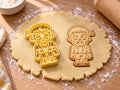 Butter-gelber Monster-Ausstecher mit Prägung neben Keks mit Kopfbolzen, Stirnnaht und zerrissener Kleidung auf hellem Holz