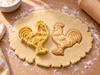 Butter-gelber Hahn-Ausstecher mit Prägung neben gebackenem Keks mit Kamm, Halsgefieder und Sichelfedern auf hellem Holz