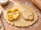 Butter-gelber Herz-Ausstecher mit Prägung neben Keks mit geschwungenem Doppellinien-Herz und Pfotenabdruck auf hellem Holz