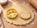 Butter-gelber Igelkopf-Ausstecher mit Prägung neben gebackenem Keks mit Zackenstacheln und runder Nase auf hellem Holz