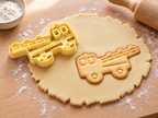 Butter-gelber Feuerwehrauto-Ausstecher mit Prägung neben gebackenem Keks mit Drehleiter und Führerhaus auf hellem Holz