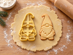 Butter-gelber Wichtel-Ausstecher mit Prägung neben gebackenem Keks mit Zipfelmütze, Knubbelnase, Bart und Füßen auf hellem Holz