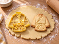 Butter-gelber Karate-Ausstecher mit Prägung neben gebackenem Keks mit Jacke, langen Ärmeln und geradem Saum auf hellem Holz