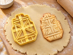 Butter-gelber Klebeband-Ausstecher mit Prägung neben gebackenem Keks mit kreuz und quer geprägten Streifen auf hellem Holz