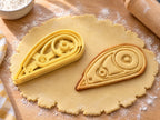 Butter-gelber Korrekturroller-Ausstecher mit Prägung neben gebackenem Keks mit zwei Spulen und schmaler Spitze auf hellem Holz
