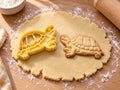 Butter-gelber Landschildkröten-Ausstecher mit Prägung neben gebackenem Keks mit gewölbtem Plattenpanzer auf hellem Holz