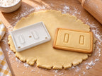 Seitenwand-Ausstecher mit Prägung neben gebackenem Lebkuchen-Keks mit zwei hohen Fenstern