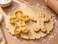Butter-gelber Lebkuchenmann-Ausstecher mit Prägung neben gebackenem Keks mit Fliege, drei Knopfpunkten und Lächeln auf hellem Holz