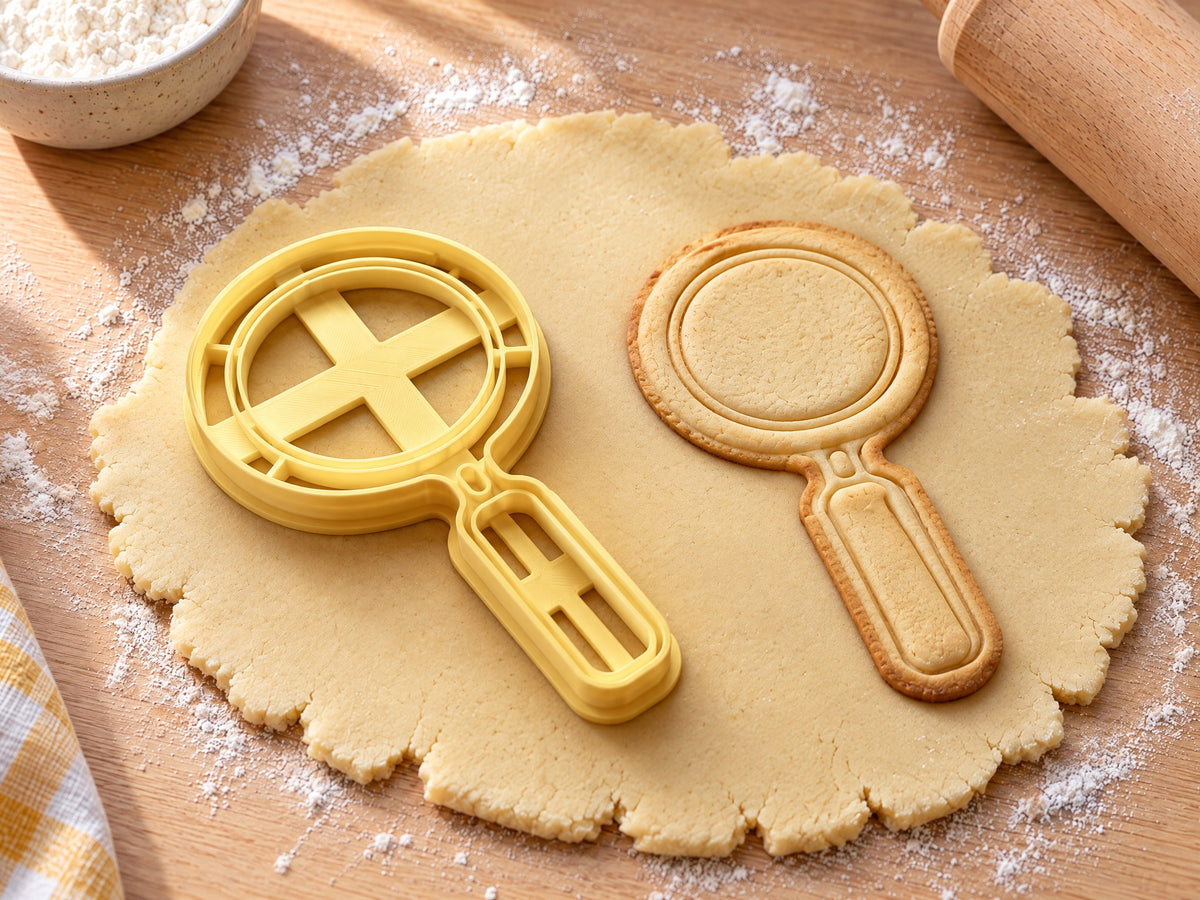 Butter-gelber Lupen-Ausstecher mit Prägung neben gebackenem Keks mit doppeltem Glasrand und Griff auf hellem Holz