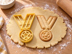 Butter-gelber Medaillen-Ausstecher mit Prägung neben gebackenem Keks mit V-Band, Öse und Stern auf hellem Holz