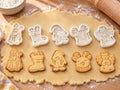 Set Nikolaus: 5 weiße Ausstecher mit Prägung, darunter die gebackenen, geprägten Kekse, auf ausgerolltem Teig und hellem Holz