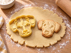 Butter-gelber Toller-Ausstecher mit Prägung neben gebackenem Keks mit Retrieverkopf, Blesse und Schlappohren auf hellem Holz
