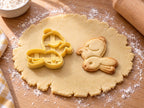 Butter-gelber Osterhasen-Ausstecher mit Prägung neben Keks mit springendem Hasen, Puschelschwanz und langen Ohren auf hellem Holz