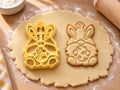 Butter-gelber Osterwichtel-Ausstecher mit Prägung neben Keks mit Hasenohren, Rauschebart und gepunktetem Ei auf hellem Holz