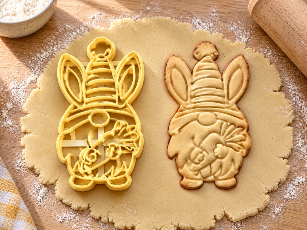 Butter-gelber Osterwichtel-Ausstecher mit Prägung neben Keks mit gestreifter Mütze, Hasenohren und Karotte auf hellem Holz