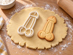 Penis lang-Ausstecher mit Prägung neben gebackenem Keks auf hellem Holz