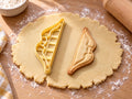 Butter-gelber Recurvebogen-Ausstecher mit Prägung neben gebackenem Keks mit geschwungenen Wurfarmen und Sehne auf hellem Holz