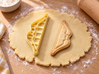 Butter-gelber Recurvebogen-Ausstecher mit Prägung neben gebackenem Keks mit geschwungenen Wurfarmen und Sehne auf hellem Holz