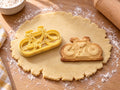 Butter-gelber Rennrad-Ausstecher mit Prägung neben gebackenem Keks mit Rahmen, Rennlenker und zwei Laufrädern auf hellem Holz