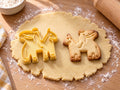 Butter-gelber Sankt-Martin-Ausstecher mit Prägung neben gebackenem Keks mit Reiter, wehendem Mantel und Pferd auf hellem Holz