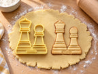 Butter-gelber Ausstecher mit Prägung als Dame und Bauer neben gebackenem Keks mit geprägten Kronen und Sockelstufen auf hellem Holz