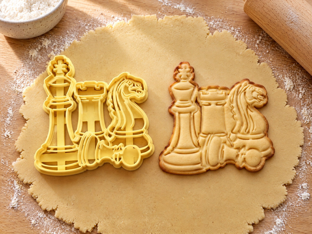Butter-gelber Ausstecher mit Prägung mit Springer, Turm, König und liegendem Bauern neben gebackenem Keks mit geprägter Mähne auf hellem Holz