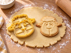 Butter-gelber Schaf-Ausstecher mit Prägung neben gebackenem Keks mit Lockenschopf, großen Augen und Lächeln auf hellem Holz