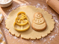 Butter-gelber Schneemann-Ausstecher mit Prägung neben gebackenem Keks aus drei Kugeln mit Lachgesicht und Schal auf hellem Holz