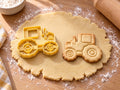 Butter-gelber Traktor-Ausstecher mit Prägung neben gebackenem Keks mit grobstolligen Reifen und Kabine auf hellem Holz