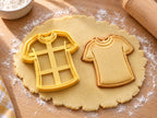 Butter-gelber Trikot-Ausstecher mit Prägung neben gebackenem Keks mit Rundhals, kurzen Ärmeln und Randlinie auf hellem Holz