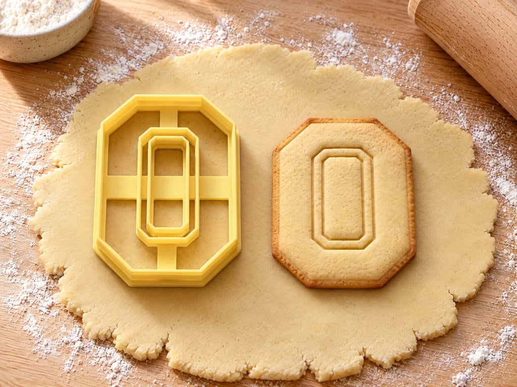 Butter-gelber Ausstecher Zahl 0 mit Prägung neben achteckigem Keks in Form einer Null mit Fenster auf hellem Holz