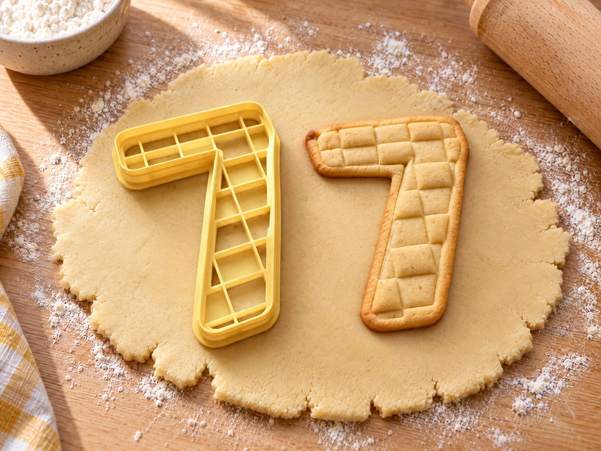 Butter-gelber Ausstecher Zahl 7 mit Prägung neben gebackenem Keks mit eingeprägten Karo-Feldern auf hellem Holz