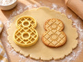 Butter-gelber Ausstecher Zahl 8 mit Prägung neben gebackenem Keks mit eingeprägtem Rautengitter auf hellem Holz