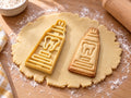 Butter-gelber Zahnpasta-Ausstecher mit Prägung neben gebackenem Keks mit Tube, Zahn-Emblem und Streifen auf hellem Holz